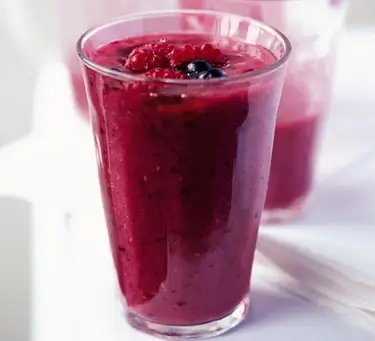 An image of a tall glass with a berry smoothie