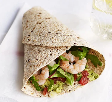 An image of a wrap filled with prawns and avocado on a plate.