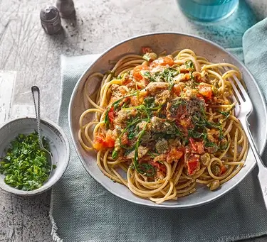 An image of pasta with sardines and tomato in a bowl.