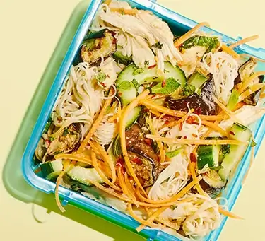 An image of noodles with chicken and vegetables in a food container.